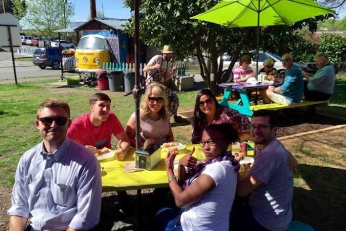 a group of people sitting at a table with an umbrella