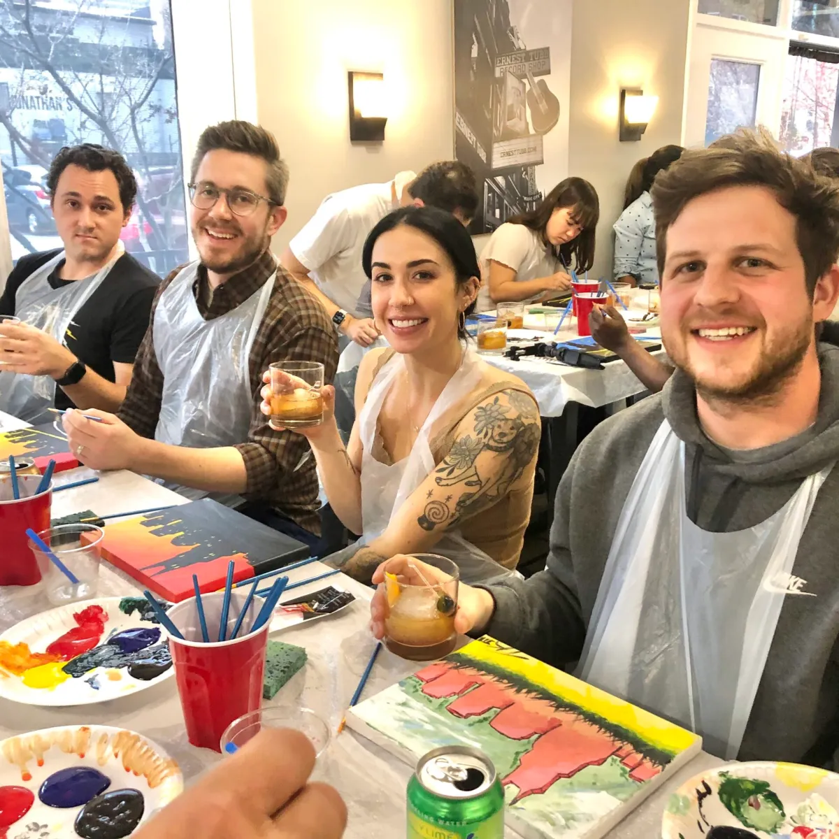 a group of people sitting at a table painting